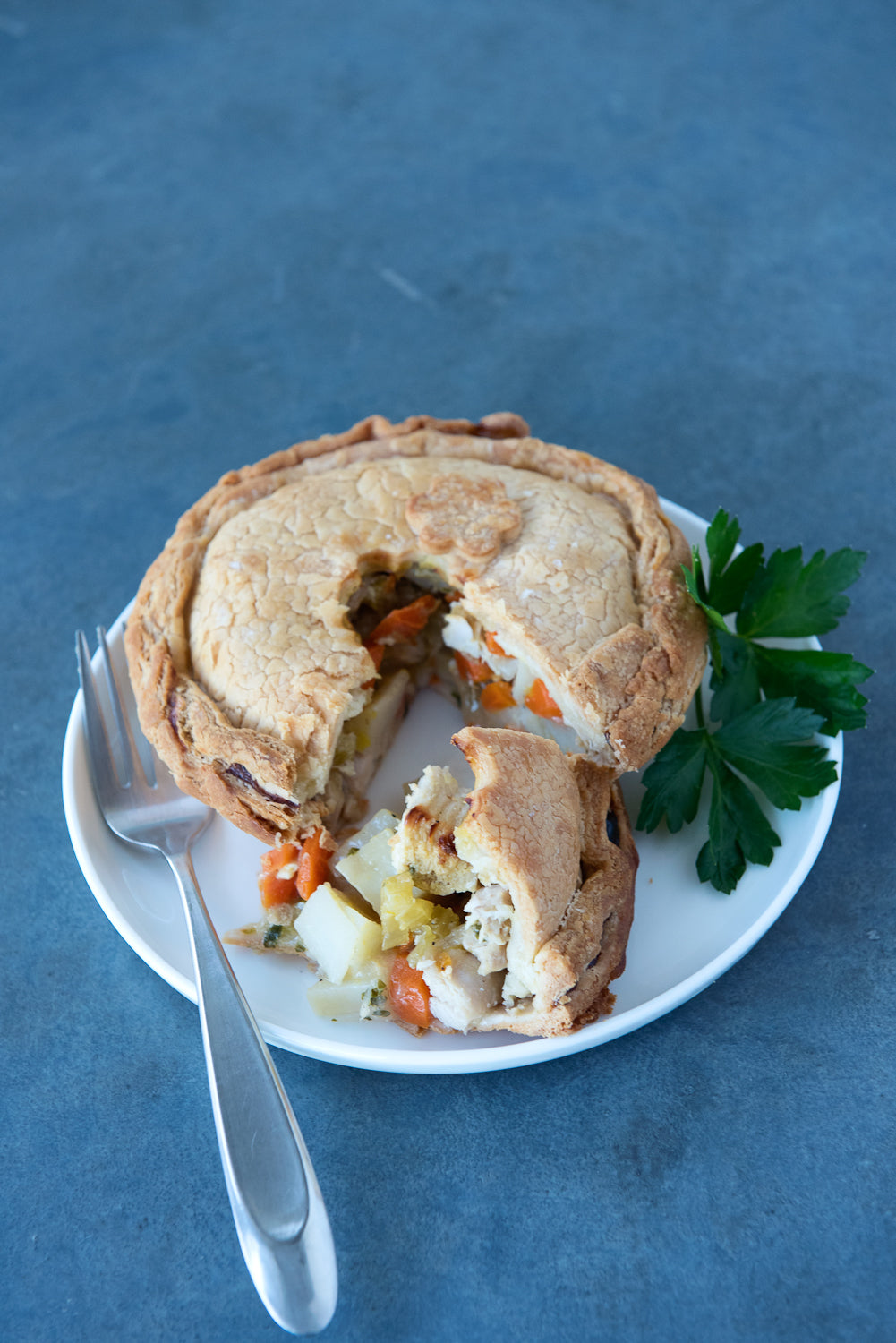 gluten free chicken pot pie on a plate with a fork & parsley