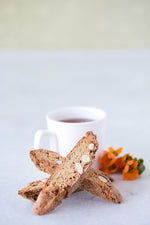 stack of 3 gluten free candied orange almond biscotti in front of cup of tea