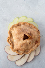 top view gluten free pie surrounded with sliced red green apples