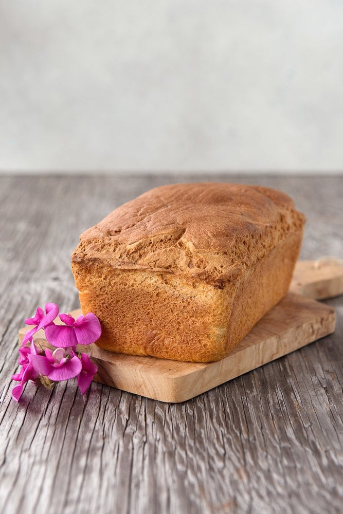 
                      
                        whole loaf gluten free Spring Bread on wood board with flower
                      
                    