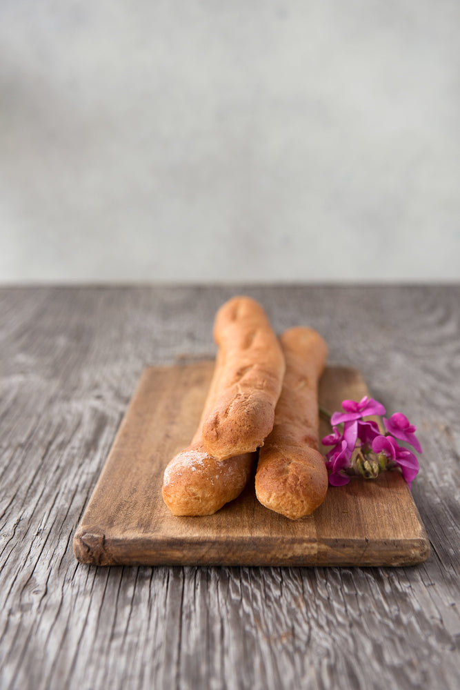 3 whole gluten free baguettes stack on cutting board with flowers