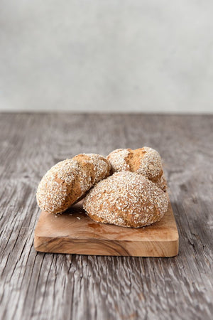 
                  
                    Load image into Gallery viewer, 3 gluten free oat bread dinner rolls piled on wood cutting board
                  
                