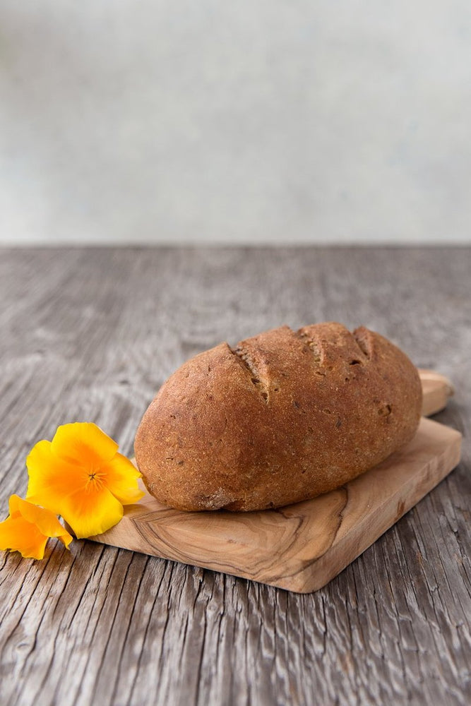 
                  
                    Load image into Gallery viewer, whole loaf gluten free Multigrain Sourdough on wood board with flower
                  
                
