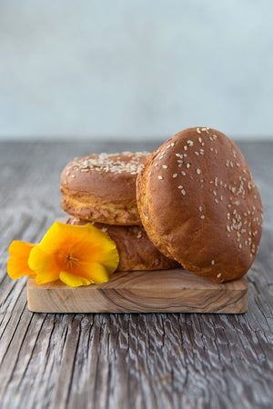 
                  
                    Load image into Gallery viewer, pile gluten free hamburger buns with sesame seeds on wood board with flowers
                  
                