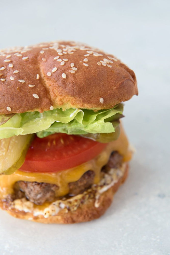 close view gluten free hamburger with lettuce tomato cheddar and dijon mayo