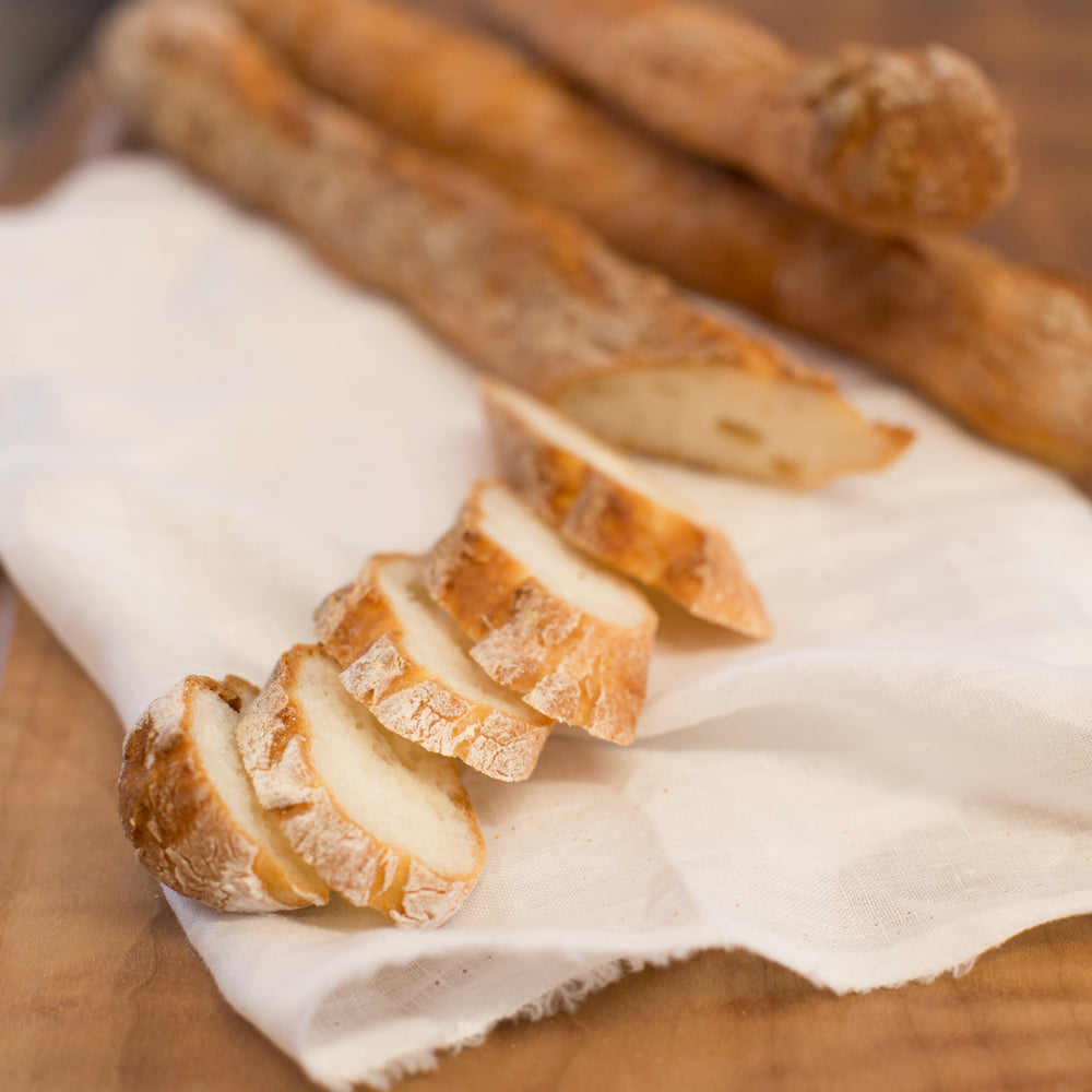 gluten free baguette slices on white cloth on wood cutting board
