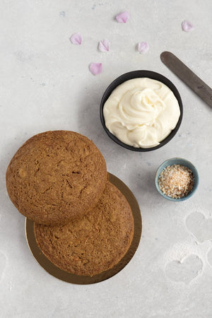 
                  
                    Load image into Gallery viewer, top view 2 gluten free plain carrot cake layers displayed with bowl of cream cheese frosting and small bowl of toasted coconut
                  
                