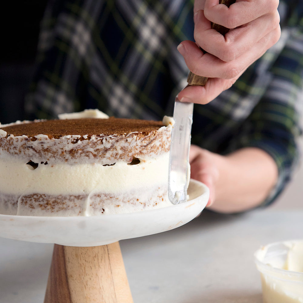 applying cream cheese frosting to gluten free carrot cake