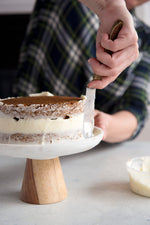 applying cream cheese frosting to gluten free carrot cake