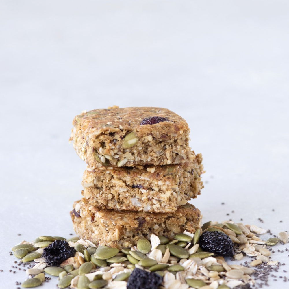 
                      
                        stack 3 gluten free granola bar squares displayed with raisins sunflower seeds oats and poppy seeds
                      
                    