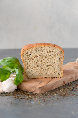 
                  
                    Load image into Gallery viewer, cut face view gluten free herb and garlic Vega bread, displayed with basil, garlic and dried herbs thyme rosemary sage
                  
                